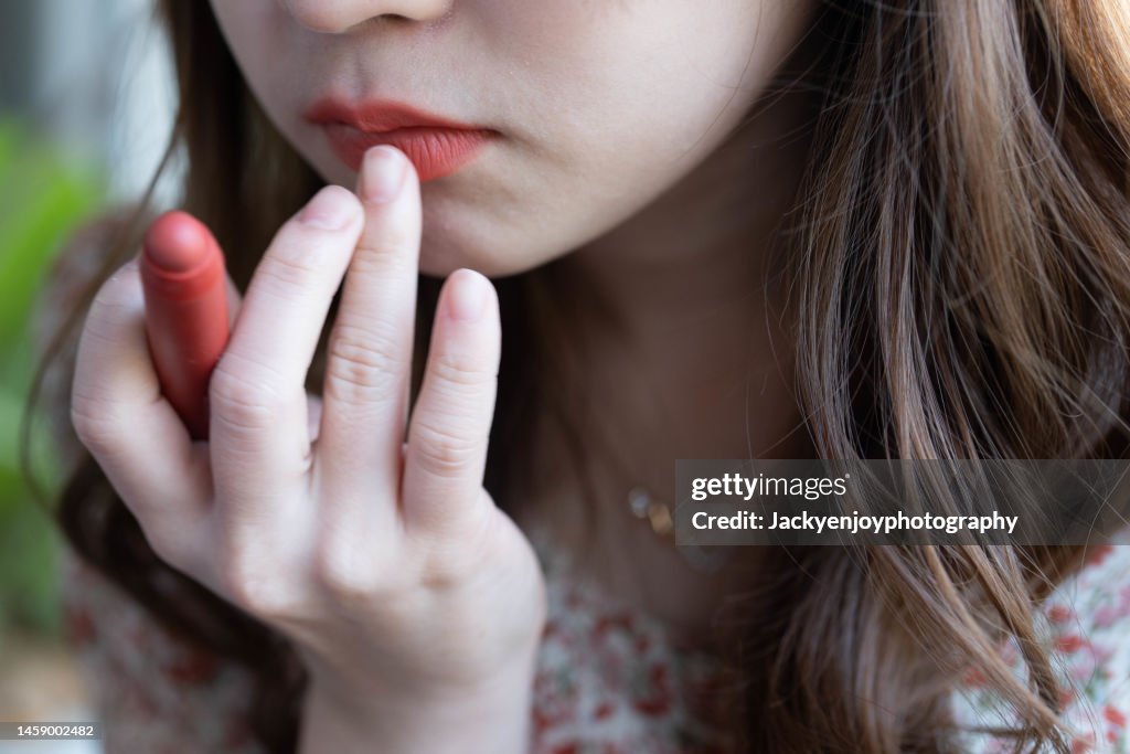 Female applying red lipstick, close up