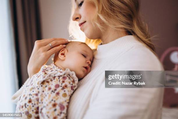 a cute infant sleeping on the mother's shoulder at home - baby girls stock pictures, royalty-free photos & images
