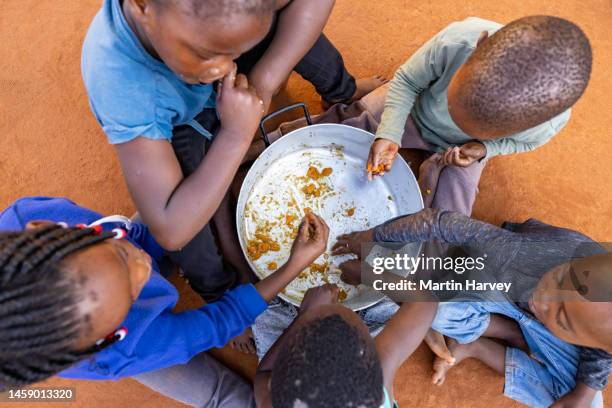 poverty in africa. hungry black african children holding out plates while a charity organisation distributes food - malnutrition stock pictures, royalty-free photos & images