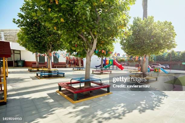 unoccupied outdoor schoolyard in strong sunshine - schoolplein stockfoto's en -beelden