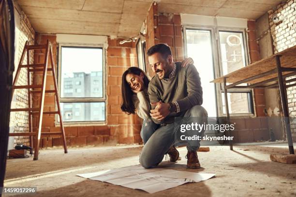 heureux couple lisant les plans dans leur appartement en rénovation. - housework photos et images de collection
