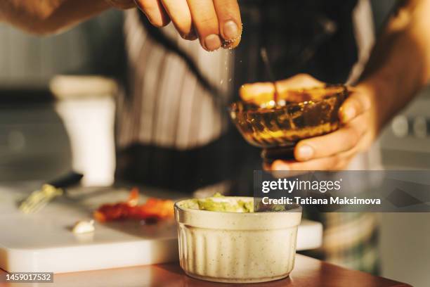 young man cooking guacamole in light kitchen at home. hands close-up. - mexicaanse-gerechten stockfoto's en -beelden