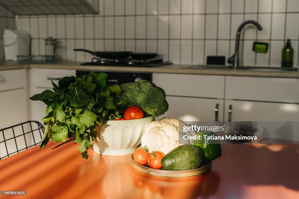 Vegetables on the table in light kitchen at home. Sunny day. The concept of cooking.
