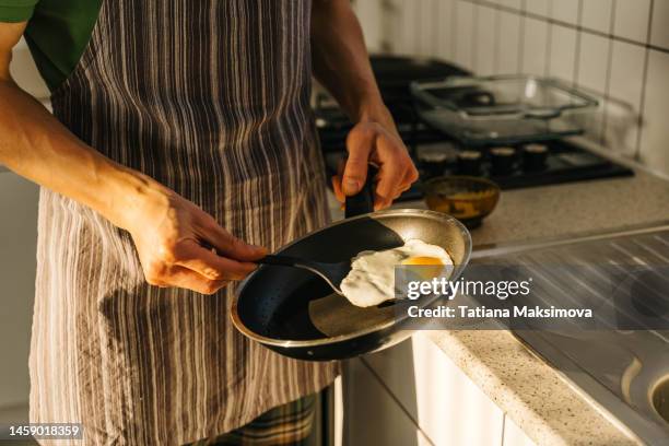 young man cooking in light kitchen at home. - fettgebraten stock-fotos und bilder