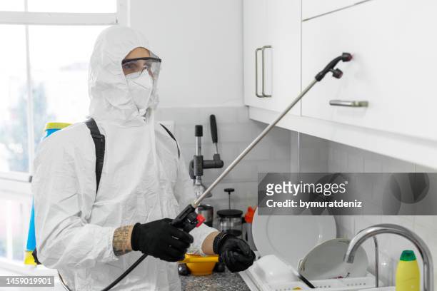 young male exterminator worker spraying insecticide chemical in kitchen - pests stock pictures, royalty-free photos & images