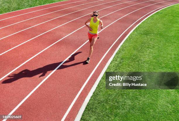 a woman running alone on a synthetic sports track painted with striped white lines. - short track imagens e fotografias de stock