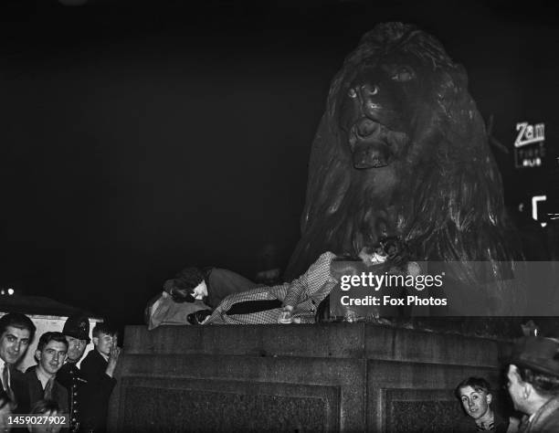 Revellers sleeping between the paws of one of Sir Edwin Landseer's lions at the base of Nelson's Column after celebrating the coronation of George VI...