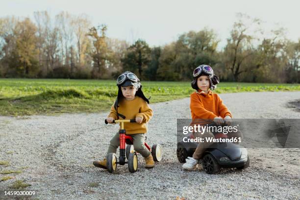 baby boy on quadcycle by brother on bobby car - bobbycar stockfoto's en -beelden
