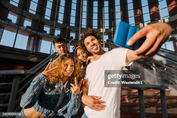 multiracial men and women taking selfie on smart phone at railroad station - geste de la main photos et images de collection