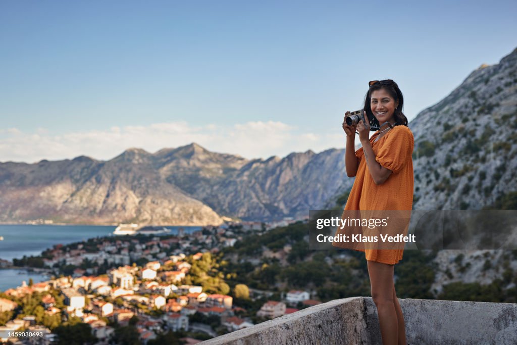 Young woman with camera against mountains