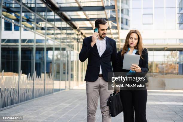 businessman telephoning and his female colleague using tablet - man lady phone ipad outside stock pictures, royalty-free photos & images