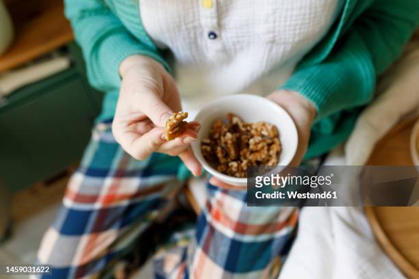 woman holding bowl of nuts at home - 核桃 個照片及圖片檔