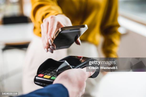 hand of young businesswoman paying through smart phone - contactless payment stock-fotos und bilder