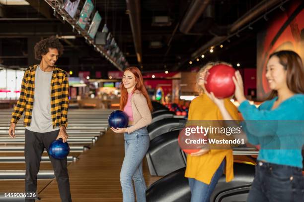 happy multiracial friends holding ball enjoying at bowling alley - man holding bowling ball stock pictures, royalty-free photos & images