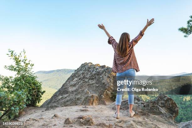 wilderness and freedom in mountains. rearview woman in plaid shirt with outstretched arms joying mountain travelling and vacation - les bras écartés photos et images de collection