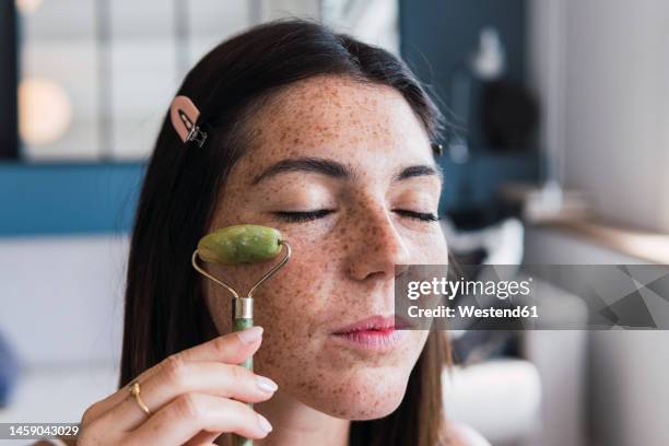 young woman with freckle face massaging using jade stone roller at home - 玉石滾輪 個照片及圖片檔