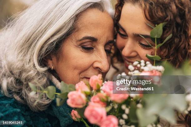 smiling young granddaughter embracing grandmother - diferença entre gerações - fotografias e filmes do acervo