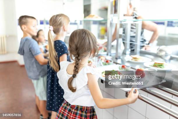 students standing side by side taking lunch in school cafeteria - edifício escolar imagens e fotografias de stock