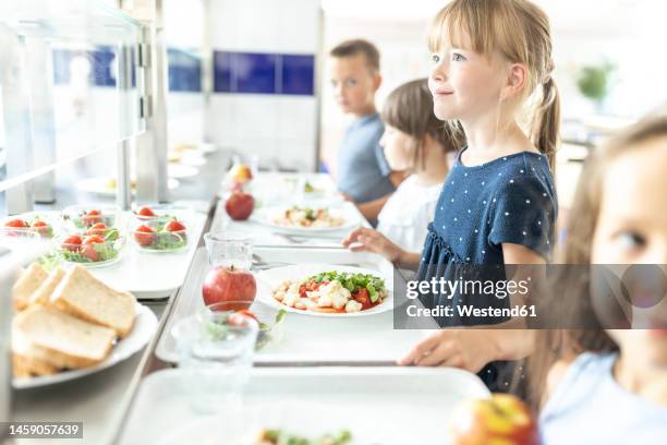 girl with blond hair holding lunch tray at school cafeteria - cantine photos et images de collection
