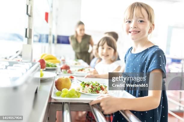 blond smiling student with healthy meal at school cafeteria - elementary school cafeteria stock pictures, royalty-free photos & images