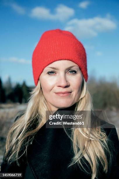 smiling mature woman wearing red knit hat - woolly hair stock pictures, royalty-free photos & images