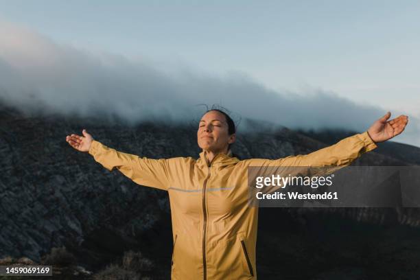 woman with eyes closed standing at caldera blanca volcano, lanzarote, canary islands, spain - arms outstretched fotografías e imágenes de stock