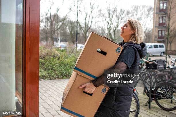 beautiful middle aged single woman moving house - mover stock pictures, royalty-free photos & images