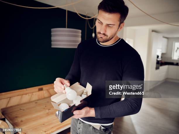man holding a box of led lightbulbs at home - bombilla de bajo consumo fotografías e imágenes de stock