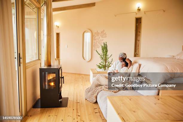 couple in bathrobes relaxing over coffee in front of a fireplace during vacation - hot wife stockfoto's en -beelden