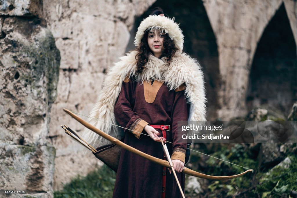 Junge mittelalterliche Kriegerin mit Pfeil und Bogen vor dem für