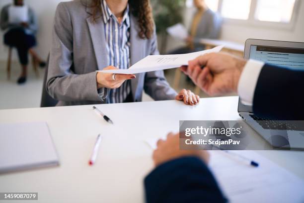 female candidate, handing to a recruiter her resume during job interview - recruter stock pictures, royalty-free photos & images