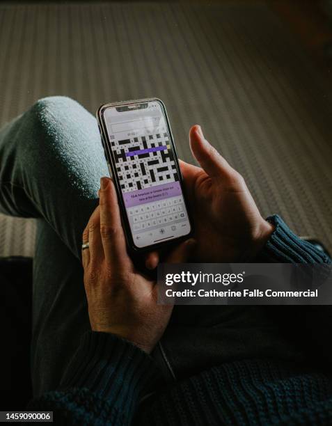 close-up of a man attempting to solve a cryptic crossword on a phone app - closing time stock pictures, royalty-free photos & images
