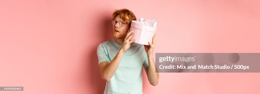 Valentines day and romance concept Handsome redhead man shaking gift