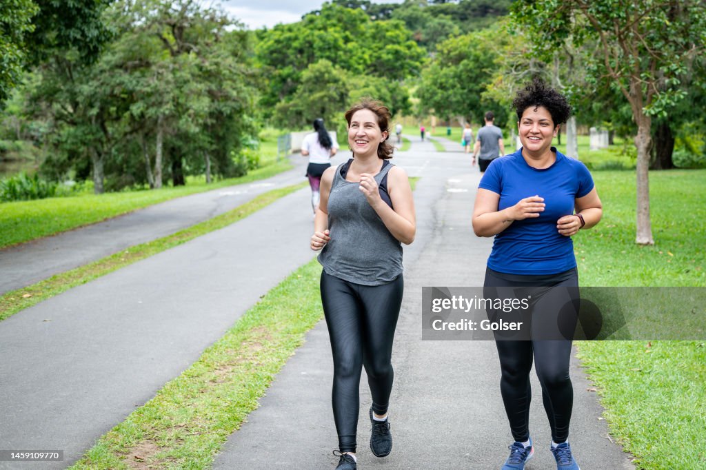 Two female friends jogging in the park