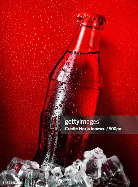 cola in ice on a red background - cola bottle photos et images de collection