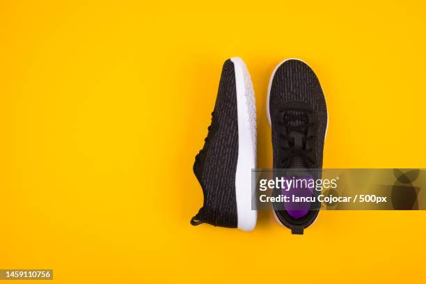 top view of black sport shoes sneakers on yellow background space for text,romania - pair stock photos et images de collection