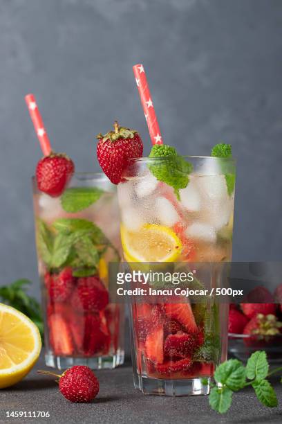 cold bright strawberry mojito cocktail with mint,lemon slices,ice cubes and drinking straw on gray,romania - alcohol detox foto e immagini stock