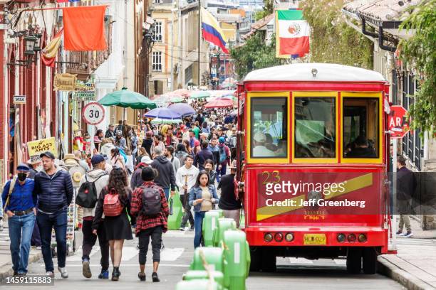 Bogota, Colombia, La Candelaria, historic district, red trolley tour bus on busy street with crowd of pedestrians.