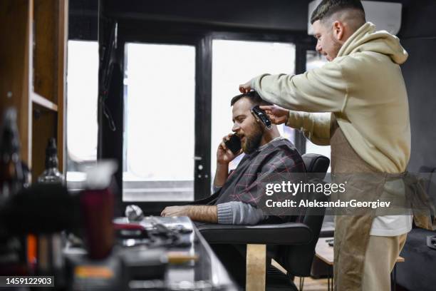 male talking on phone while getting new haircut - hair color saloon stock pictures, royalty-free photos & images