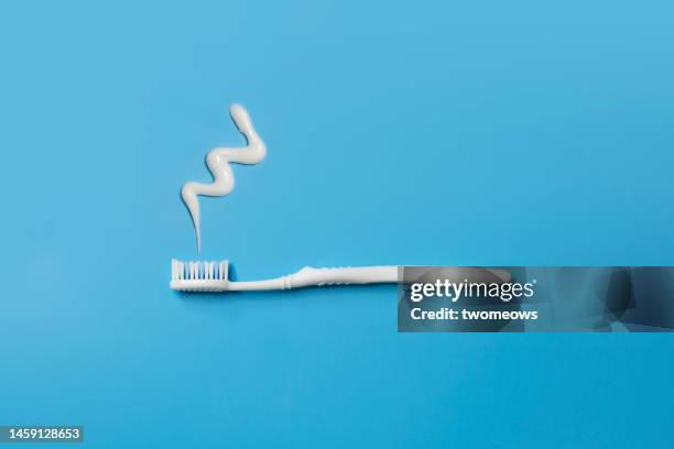flat lay white toothbrush and tooth paste on blue background. - zahnpasta stock-fotos und bilder