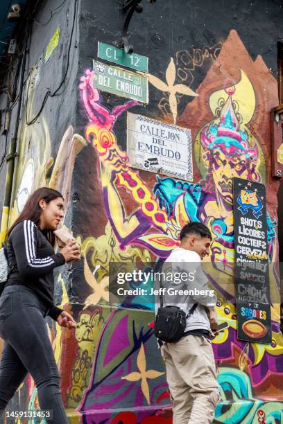 Bogota, Colombia, La Candelaria, pedestrians walking by mural artwork.