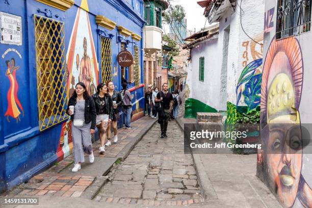 Bogota, Colombia, La Candelaria, Calle del Embudo, with mural art and pedestrians.