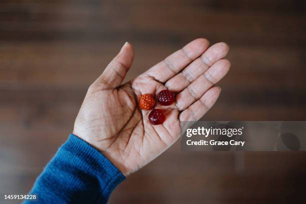 woman holds fruit-flavored gummy nutritional supplements - bonbon stock-fotos und bilder