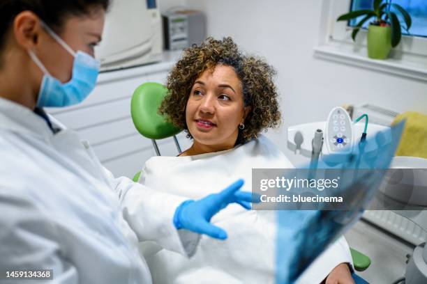 dentist explaining tooth x-rays to a female patient - implante dentário imagens e fotografias de stock