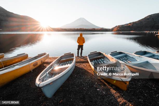 person admiring the mount fuji from the banks of a lake at sunrise, japan - fujikawaguchiko stock-fotos und bilder