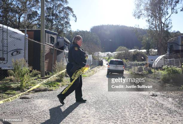 San Mateo County sheriff deputy pulls police tape across a driveway at a farm where a mass shooting occurred on January 24, 2023 in Half Moon Bay,...