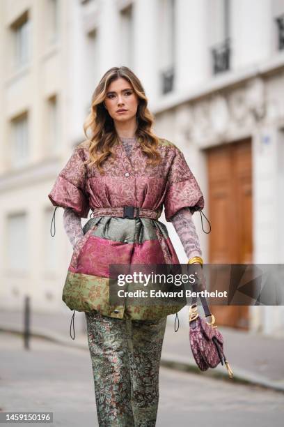 Zita D'Hauteville wears a pale purple and black print pattern wool pullover, a purple / green / burgundy shiny leather with embossed pattern belted /...