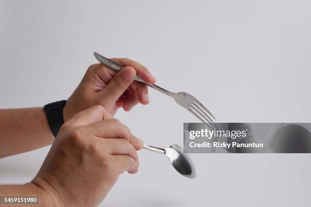 cropped hands holding fork and spoon against white background - spoon in hand stock pictures, royalty-free photos & images
