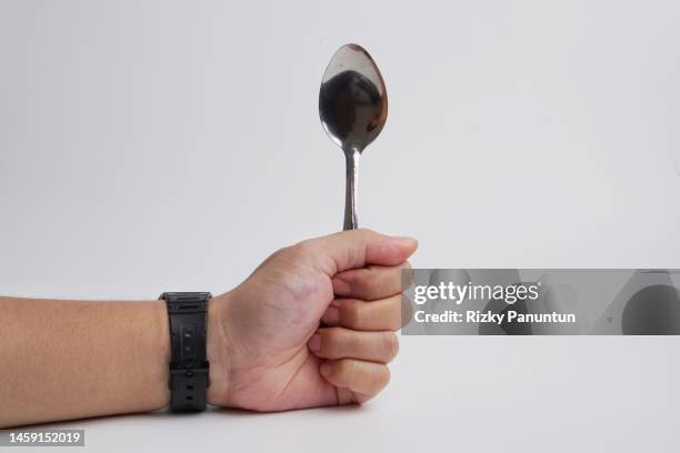 hand holding a spoonagainst white background - spoon stock pictures, royalty-free photos & images