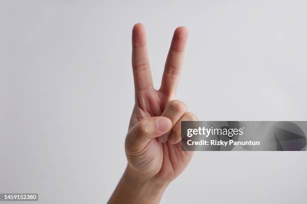close-up of male hand doing "peace" sign - gesto de victoria fotografías e imágenes de stock